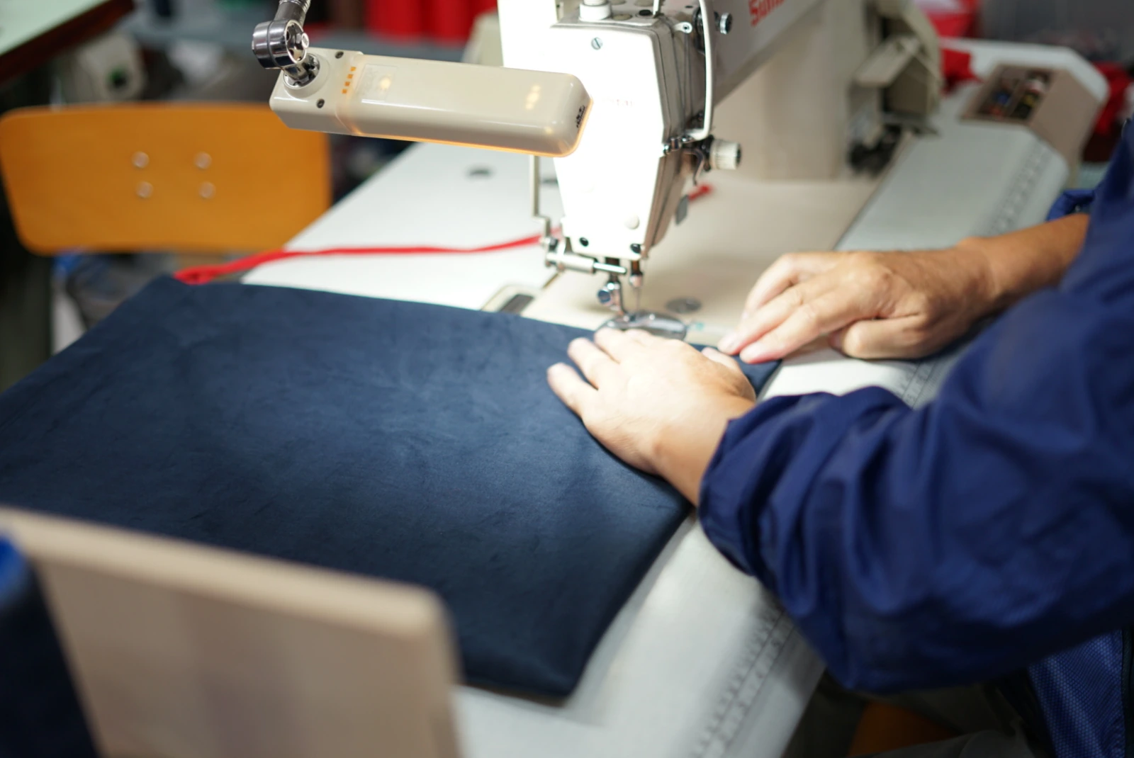 Sastre cosiendo uniformes en taller propio